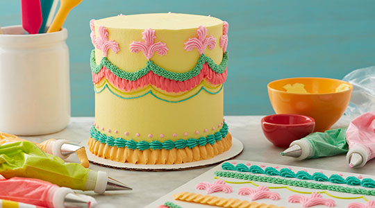 Lambeth-style cake decorated with buttercream dots, fleur de lis, swags.